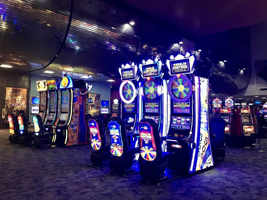 A bank of Wheel of Fortune 3D cabinets on a casino floor, the marketing label 3D slots carries online