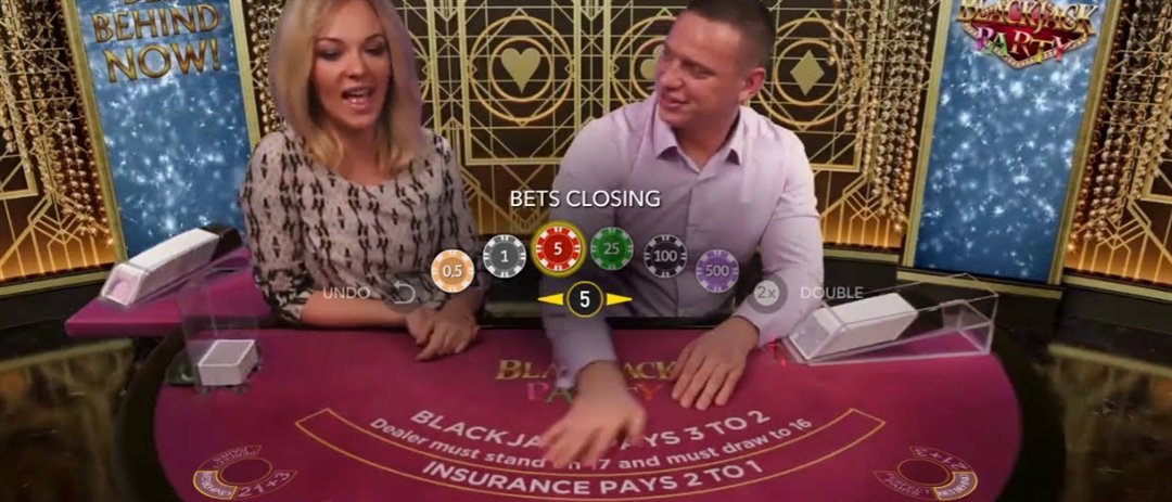 The blackjack party live table with two hosts and the felt printing Blackjack Pays 3 to 2, Dealer must stand on 17 and Insurance Pays 2 to 1