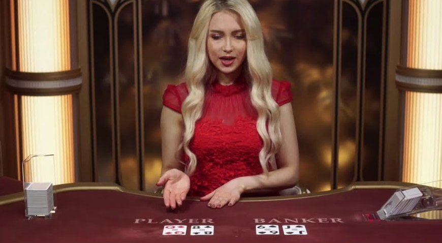 A lightning baccarat live dealer in a red dress at the table in the Art Deco studio with pillars of light