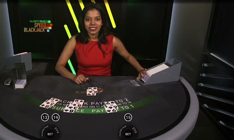 Majority Rules Speed Blackjack dealer with cards dealt on the two-seat table under the Majority Rules Speed Blackjack logo
