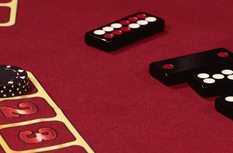 Pai gow tiles dominoes set on a red casino felt beside a stack of chips and numbered seats