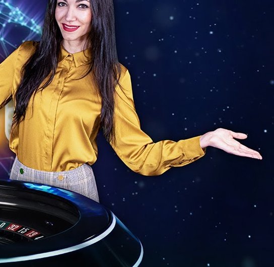 Quantum Roulette presenter in a gold blouse beside the neon-lit Quantum wheel