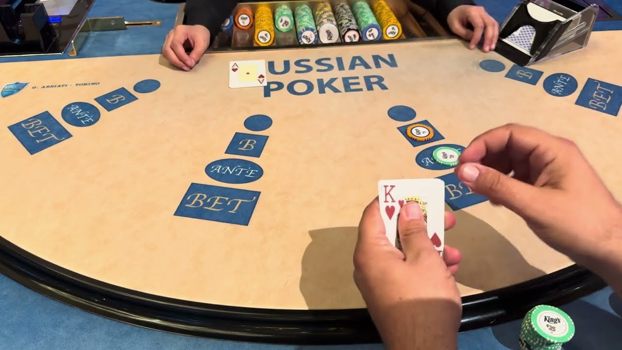 A Russian Poker table with Ante and Bet boxes at each seat and a player holding the King of hearts