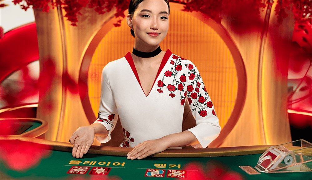 Seotda Baccarat dealer at the green table with Player and Banker boxes labelled in Korean and Hwatu cards dealt