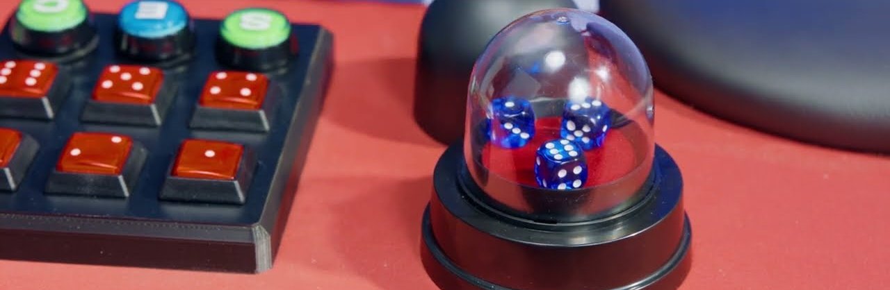 A sic bo automatic shaker dome holding three dice beside the dealer control panel
