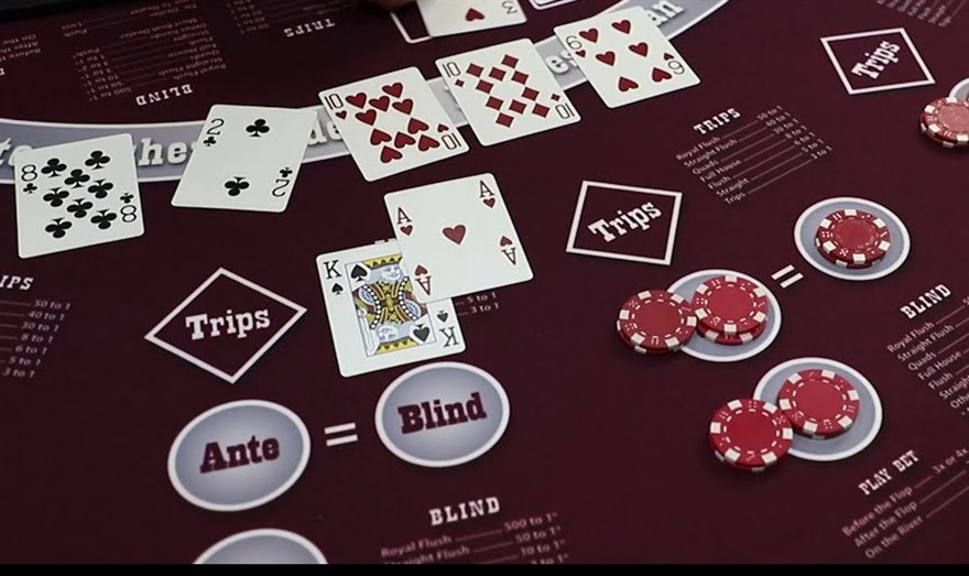 A close view of an Ultimate Texas Holdem felt with community cards, chips on the Ante and Blind circles and the Trips paytable