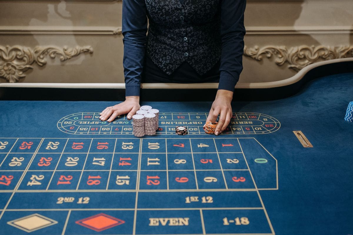 Dealer's hands arranging chips on a blue roulette table in a casino, the setting behind a 20 dollar no deposit bonus Canada offer