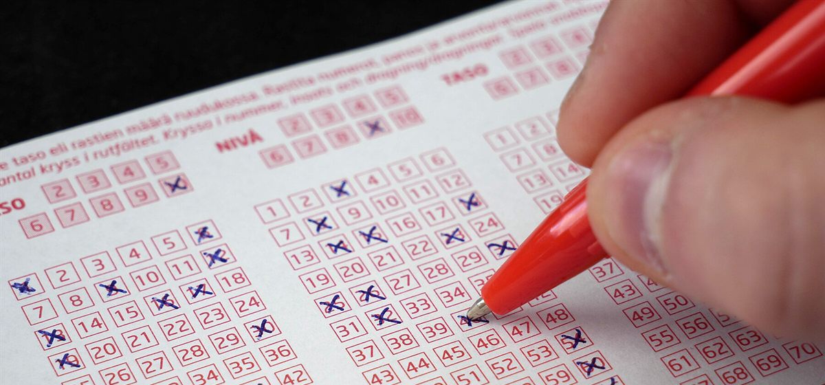 A player marking numbers on a keno ticket with a red pen, the first step of any keno strategy Canada players use