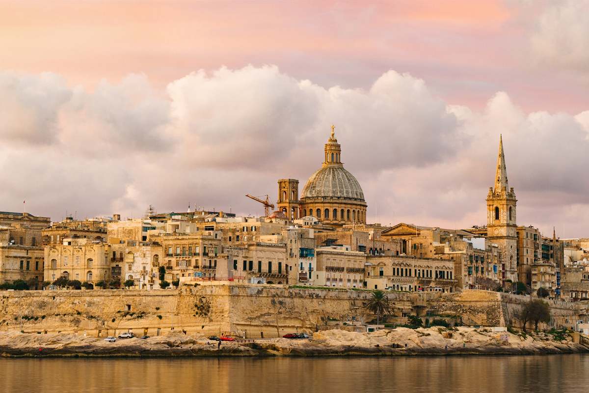 Valletta skyline at sunset with the Carmelite dome and St Paul spire above the harbour