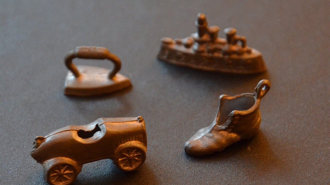 Classic Monopoly tokens, an iron, battleship, car and boot, the board game behind Monopoly slots Canada players spin