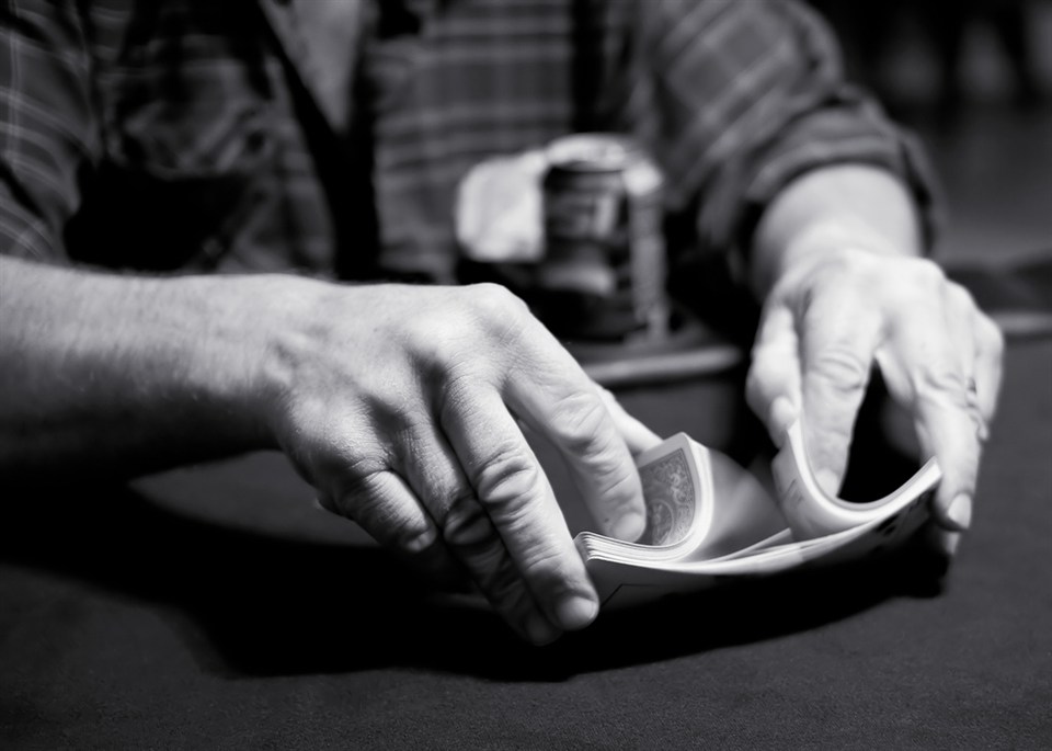 Black and white photo of a dealer riffling cards on a poker table