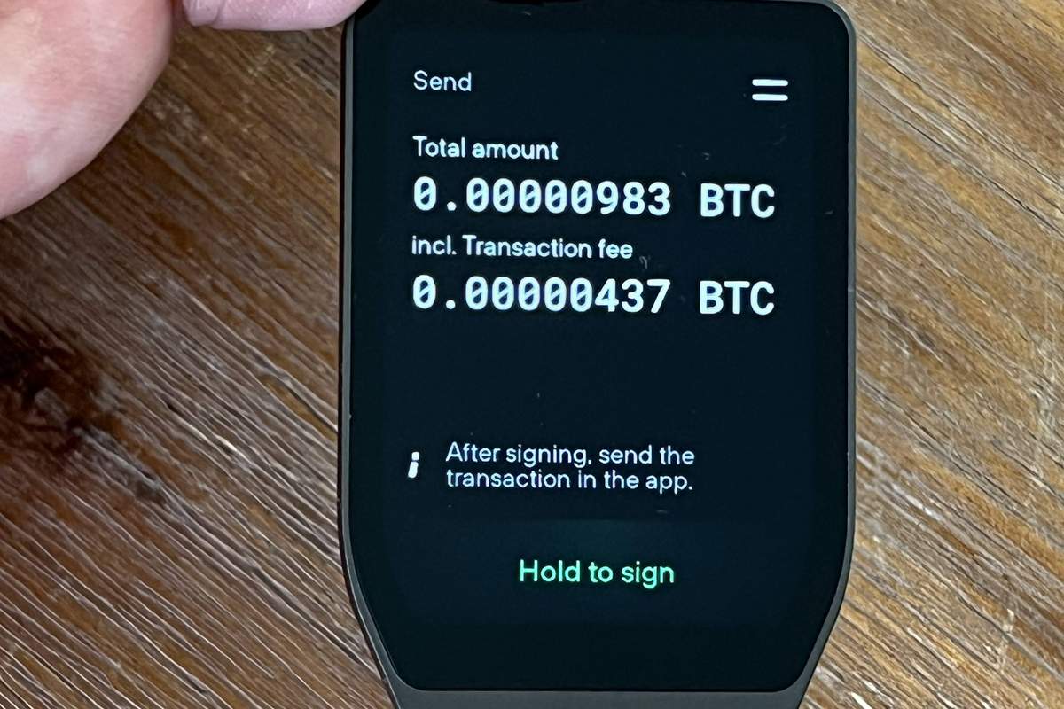 Hardware wallet in hand showing a send screen before signing a crypto transfer