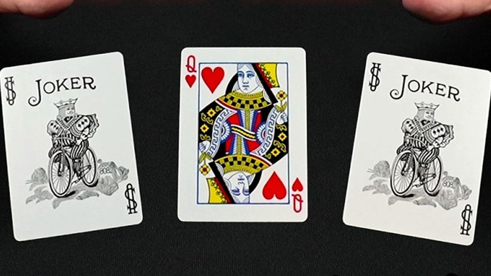 Three card monte Canada: a queen of hearts between two jokers on a black table